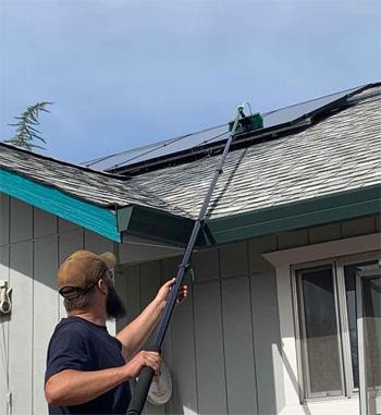 Man Washing Solar Panels on Roof